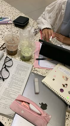 an apple laptop computer sitting on top of a table covered in clutter and papers