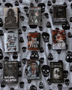 there are many different books on the bed sheet that is covered in skulls and bones