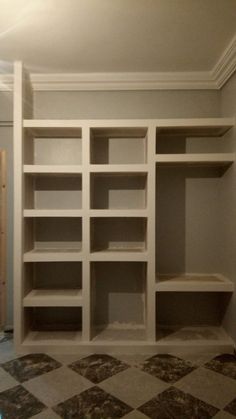 an empty room with white shelves and checkerboard flooring in the middle of it