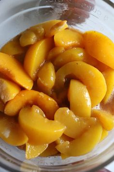 a glass bowl filled with sliced peaches on top of a table