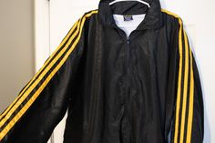 This Vintage 1990's Black Track Jacket With Racing Stripes is in good vintage condition.  This windbreaker jacket is black with three yellow racing stripes. It has a soft white polyester and cotton lining and can be worn during the spring or fall months as a light jacket. . Tag says Exportman Sportswear. Size L. Measurements laying flat: Length - 26 inches Chest - 27 inches Waist - 19 inches Sleeves - 32 inches Stripes Outfit, Polka Dot Maxi Dresses, Stripe Outfits, Racing Stripes, Vintage Streetwear, Yellow Stripes, Track Jacket, Light Jacket, Black Jacket