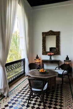 a table with fruit on it sitting in front of a window next to a black and white checkered floor