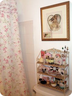 a bath room with a toilet and a shelf next to a shower curtain that has flowers on it