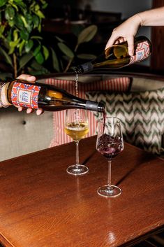 someone pouring wine into two glasses on a table