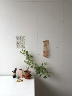 a white table topped with potted plants next to a piece of paper hanging on the wall