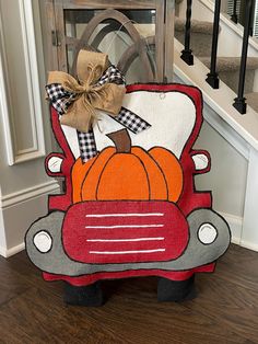 a red car with pumpkins on the hood is sitting in front of some stairs