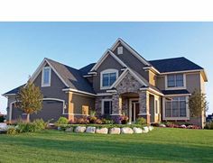 a large house with lots of windows and landscaping on the front lawn, surrounded by green grass