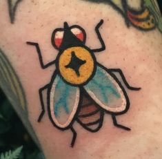 a close up of a tattoo with a bee on it's arm and another insect in the background