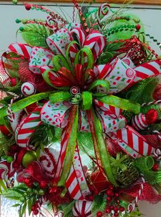 a christmas wreath with candy canes and bows on the front door, hanging from a wall