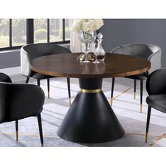 a round dining table with black chairs and gold trimmings on the legs, in front of a large window