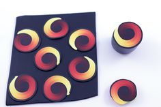 several circles are arranged on top of a piece of black paper with red, yellow and orange designs