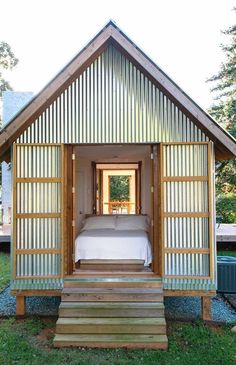 a small wooden cabin with a bed in the doorway and steps leading up to it