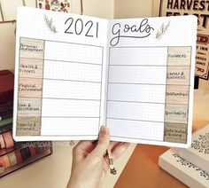 a person holding up a planner with the words 2021 goals written on it in front of them