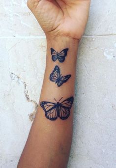 a woman's wrist tattoo with three butterflies on the left side of her arm