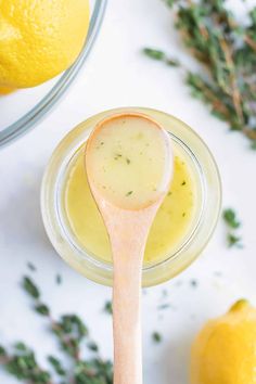 a spoon full of lemon butter next to some lemons and thyling sprigs