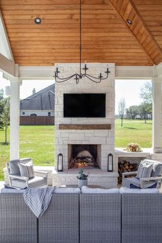 an outdoor living area with couches, fireplace and flat screen tv on the wall