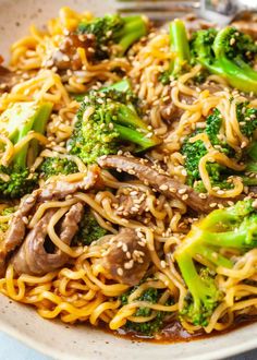 broccoli, noodles and beef are in a bowl with a fork on the side