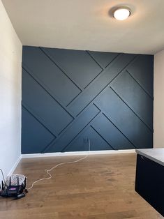 an empty room with wood flooring and blue painted wall in the background, there are electrical cords on the floor