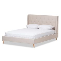 an upholstered bed with white sheets and pillows