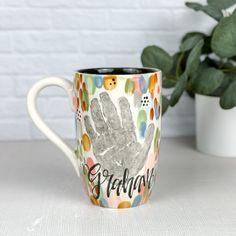 a coffee mug with a handprinted design on the side and words grandma next to it