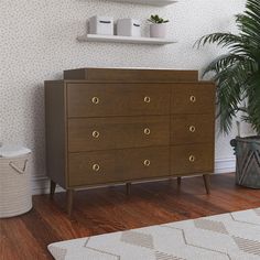 a wooden dresser sitting next to a potted plant on top of a hard wood floor