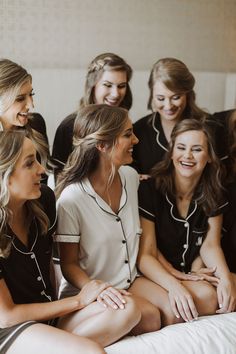 a group of young women sitting on top of a bed next to each other smiling