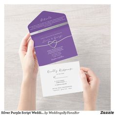 a person holding up a purple and white wedding card