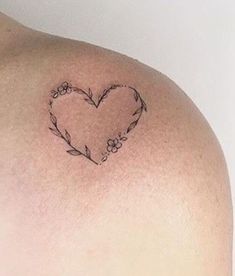 a woman's shoulder with a heart tattoo on it