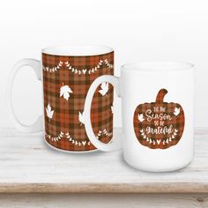 two coffee mugs sitting on top of a wooden shelf with the words, it's all season and grateful