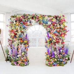 an arch made out of flowers in front of a window