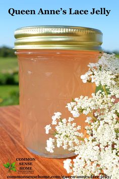 a jar filled with liquid sitting on top of a wooden table next to white flowers