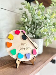 a wooden toy with hearts on it sitting on a shelf next to a potted plant