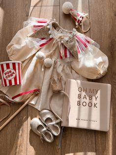 an open book on the floor next to baby shoes and other items that are laying around