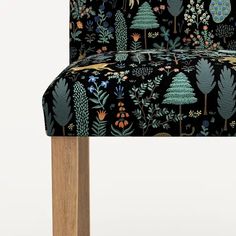 an upholstered chair with trees and flowers on it