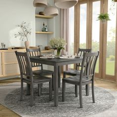 a dining room table and chairs in front of large windows