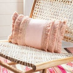 a pink pillow sitting on top of a wicker chair