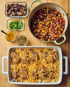 a casserole dish filled with beans, corn and other toppings on a wooden table