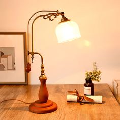 a desk lamp sitting on top of a wooden table next to a bottle of wine