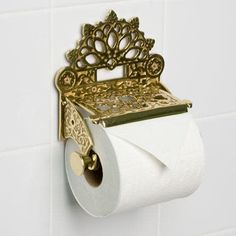 a gold toilet paper holder with a crown on it's back and a roll of toilet paper in front of it