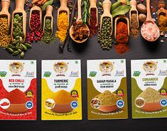 several different types of spices and spoons lined up on a table with labels for them