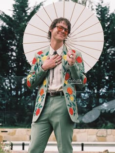 a man in a suit and sunglasses holding an umbrella