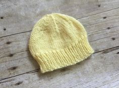 a yellow knitted hat sitting on top of a wooden floor