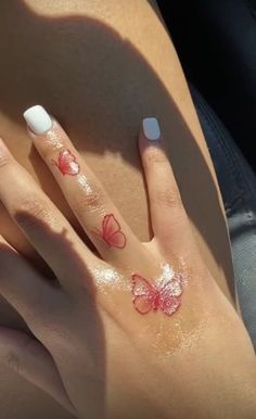 a woman's hand with butterfly tattoos on her left thumb and the other half of her finger