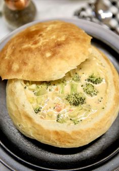 a pot pie with broccoli and cheese in it sitting on a black plate