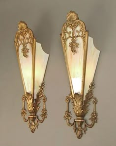 two wall sconces with white and gold glass shades on the sides, one light up