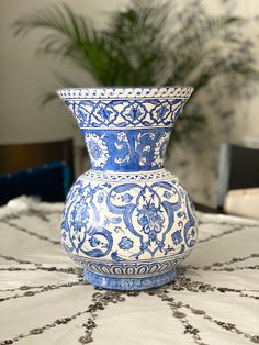 a blue and white vase sitting on top of a table next to a potted plant