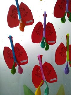 paper flowers and spoons hanging from strings in front of a glass wall with water droplets on them