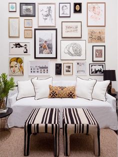 a living room filled with lots of framed pictures on the wall above a white couch