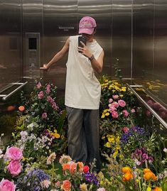 a man standing in front of flowers using his cell phone