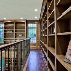 a wooden book shelf filled with lots of books next to a stair case in a home